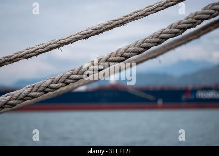 Trois cordes parallèles en nette mise au point menant vers un grand cargo bleu flou Banque D'Images