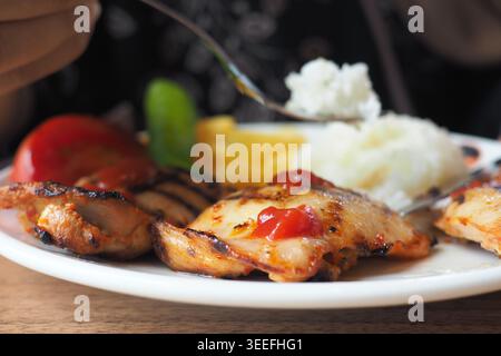 Délicieux poulet grillé servi sur une assiette avec du riz Banque D'Images