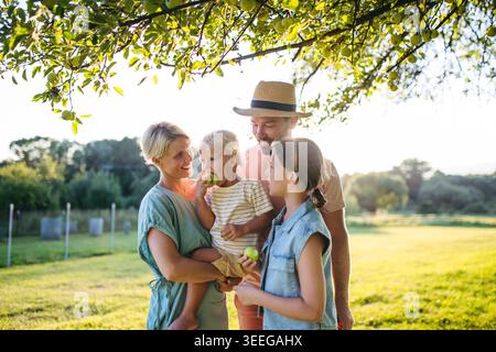 Famille en promenade dans la nature estivale, debout sous le pommier. Banque D'Images