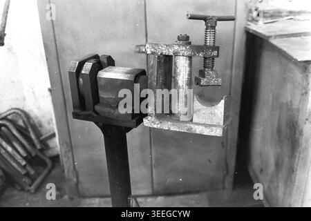 Slaviansk, 1983. Dans un atelier de l'armature-Insulator Factory (AIZ). Gros plan d'un étau mécanique spécialisé ou d'un dispositif de pressage monté sur un support métallique robuste, conçu pour des opérations spécifiques de travail des métaux ou d'assemblage. Cette photographie vintage en noir et blanc capture l'atmosphère authentique de l'époque, reflétant les activités quotidiennes et la culture industrielle de la région pendant la période soviétique. Il sert de document historique précieux de la communauté locale, préservant la mémoire visuelle et mettant en valeur un Donbass paisible. Banque D'Images