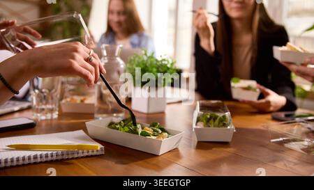 Les employés de bureau mangent des salades ensemble pendant la pause déjeuner. Banque D'Images