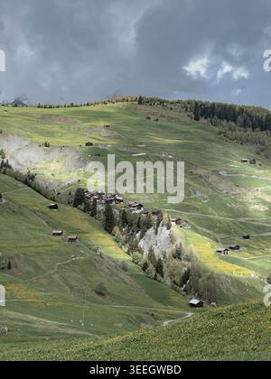 Panorama spectaculaire sur les montagnes à Graubünden, en Suisse, avec des prairies alpines verdoyantes, des villages, des forêts et des nuages orageux sur les Alpes suisses. Banque D'Images