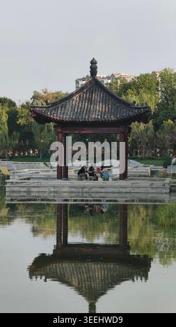 Pavillon chinois traditionnel sur le lac avec des gens se relaxant au coucher du soleil Banque D'Images