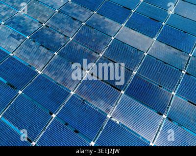 Vue aérienne de la centrale solaire flottante SolarSea avec panneaux photovoltaïques bleus disposés en grille géométrique au-dessus de l'océan à Dharavandhoo, Baa Banque D'Images
