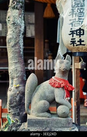 Statue de renard kitsune en pierre dans un sanctuaire japonais Inari avec lanterne en papier et détails traditionnels du sanctuaire au Japon Banque D'Images