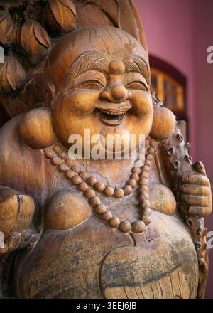 Détail en gros plan d'une sculpture de statue de Bouddha riant en bois altérée avec un collier de perles de prière, George Town, Penang, Malaisie Banque D'Images