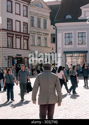 Les piétons traversent la place pavée ensoleillée de la vieille ville de Tallinn par une chaude journée de printemps, Estonie Banque D'Images