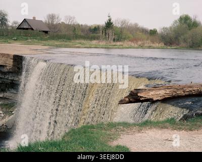 L'eau coule sur la large cascade de Jägala avec une bûche altérée sur le bord, rivière Jägala, Estonie, au printemps Banque D'Images