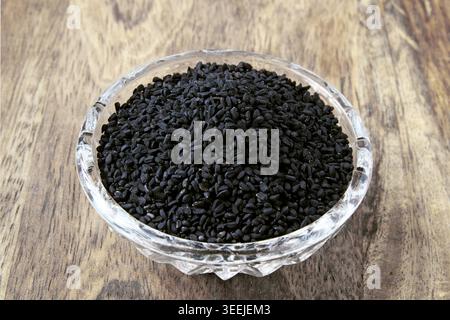 graines de cumin noir dans un bol en cristal sur une table en bois Banque D'Images