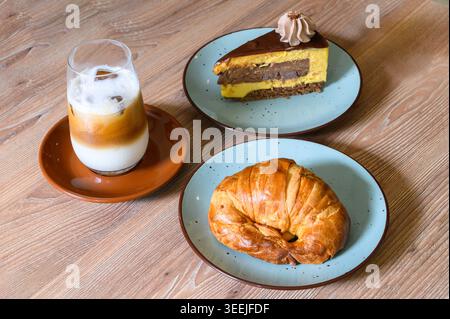 Latte glacé, croissant et gâteau au chocolat sur une table en bois Banque D'Images