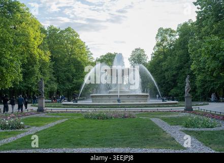 Grande fontaine en pierre éclaboussant de l'eau au centre d'un parc verdoyant de la ville. Banque D'Images