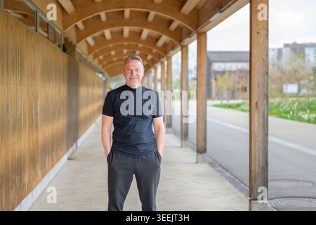 Portrait pleine longueur d'un homme d'affaires mature détendu debout avec les mains dans les poches sous l'architecture moderne en bois. style de vie professionnel Banque D'Images