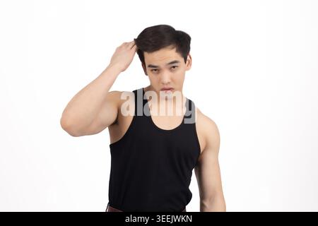 Homme en débardeur noir fixant ses cheveux et posant pour la haute qualité professionnona... Banque D'Images