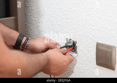 Électricien testant une prise électrique avec un multimètre numérique Banque D'Images