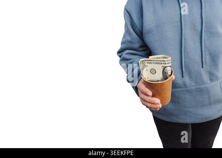Gros plan d'un pauvre homme tenant une tasse de papier jetable avec un billet d'un dollar sur fond blanc. Le thème est pauvreté, sans-abri Banque D'Images