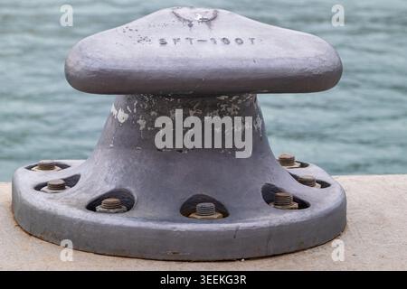 Borne d'amarrage robuste en fonte boulonnée à une jetée en béton, assurant la sécurité maritime Banque D'Images