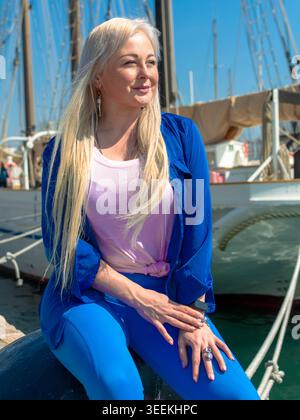 Femme blonde se relaxant dans le port de yacht le jour ensoleillé Banque D'Images