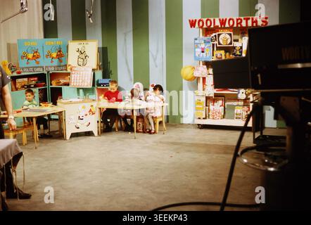 Une photographie documentaire d'archives du début des années 1970 montrant une salle de classe reconstruite ou un ensemble d'activités intérieures avec une enseigne de Woolworth bien en vue, des enfants assis sur des bureaux et des étagères d'exposition. Banque D'Images