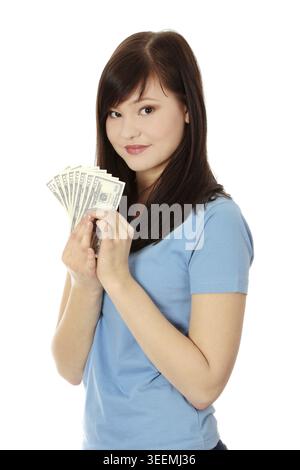 Jeune brune aux cheveux longs tenant un dossier de billets en dollars. Satisfait jeune, femme avec de l'argent portant un t-shirt bleu et regardant droit. Isolé sur th Banque D'Images