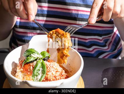 Portion de lasagne, lasagnes cuites au four, couches de pâtes avec fromage, viande hachée, tomate. Lasagne sur la table de restaurant de rue sur une journée d'été ensoleillée, floue Banque D'Images
