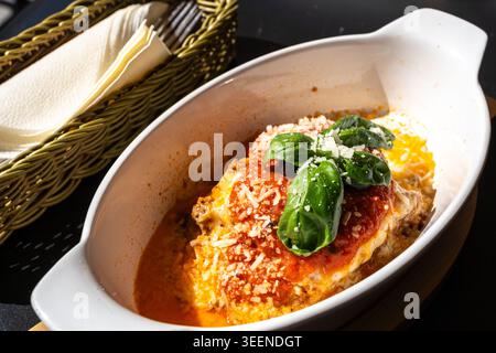 Portion de lasagne, lasagnes cuites au four, couches de pâtes avec fromage, viande hachée, tomate. Lasagne sur la table de restaurant de rue sur une journée d'été ensoleillée, floue Banque D'Images