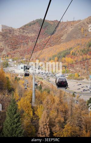 Télécabines se déplaçant au-dessus de la forêt de montagne d'automne à Shymbulak, Kazakhstan. Banque D'Images