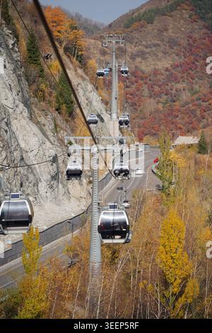 Télécabines se déplaçant au-dessus de la forêt de montagne d'automne à Shymbulak, Kazakhstan. Banque D'Images