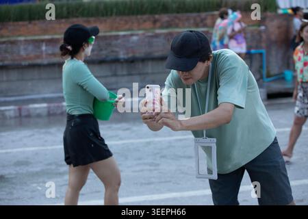 CHIANG mai, THAÏLANDE-APR 15, 2026 : touriste masculin prenant des photos avec smartphone, fête de l'eau de Songkran en Thaïlande, profil latéral Banque D'Images