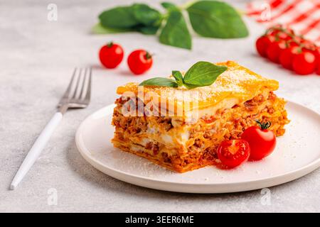 Lasagne traditionnelle à la sauce bolognaise garnie de feuilles de basilic servies sur une assiette blanche Banque D'Images