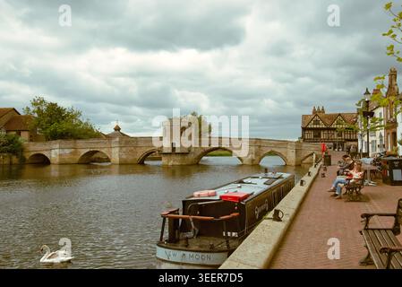 Les gens assis sur le quai à côté de la rivière Great Ouse et St Ives Bridge dans le Cambridgeshire, Angleterre, Royaume-Uni Banque D'Images