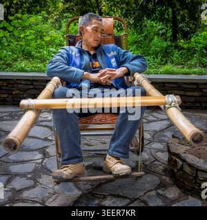 Homme reposant sur une chaise portée, Wulong, Chine Banque D'Images