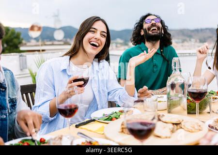 Amis appréciant le dîner barbecue arrière-cour riant sur une terrasse Banque D'Images