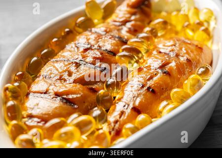 Filets de maquereau fumé avec capsules d'huile de foie de morue dans un plat blanc. Concept sain de régime Oméga 3 Banque D'Images