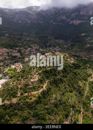 Vue aérienne du village historique de Valldemossa avec ses bâtiments en pierre nichés parmi les collines verdoyantes et les montagnes de Tramuntana à Valldemossa Banque D'Images