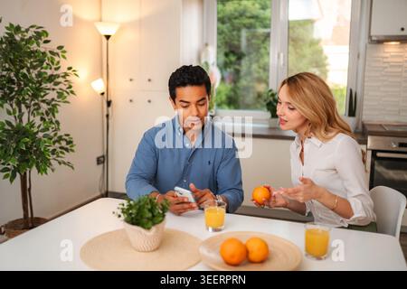 Jeune couple prenant le petit déjeuner et parlant dans la cuisine Banque D'Images
