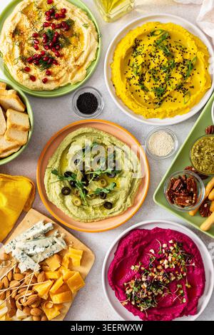 Une planche de charcuterie vibrante présente du brocoli, du curcuma, du houmous classique et de la betterave, associés à des olives, craquelins, et garnitures fraîches, parfait pour Banque D'Images
