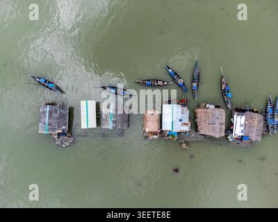 Vue aérienne du village flottant de Kalabagi avec des bateaux traditionnels en bois amarrés à côté de maisons au toit de chaume sur l'eau Khulna District, Khulna Divisi Banque D'Images