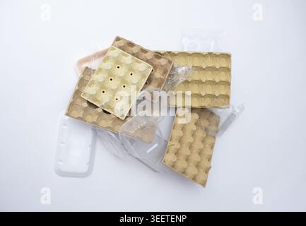 Un gros plan de haut en bas montre une pile densément emballée de cartons d'oeufs de pulpe usagés de différentes tailles et couleurs, mélangés avec des récipients en plastique transparent et un Banque D'Images