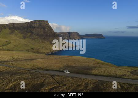 Vue aérienne d'un camping-car blanc garé sur une route côtière le long de falaises spectaculaires et de la mer bleue dans l'île de Skye, Royaume-Uni. Banque D'Images