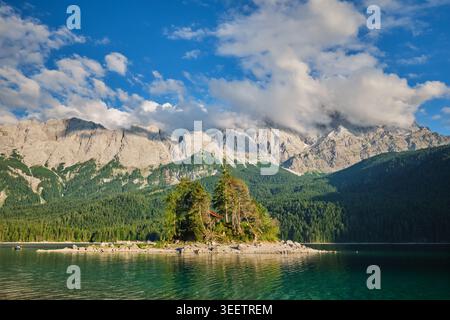 Perspective rapprochée d'une petite île couverte d'arbres dans le lac Eibsee avec les pics rocheux spectaculaires de Zugspitze en Bavière, Allemagne. Banque D'Images