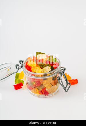 Bonbons gélifiés colorés dans un pot sur fond blanc. Concept de gummies à la mode. Gelée sucreries esthétiques. Banque D'Images