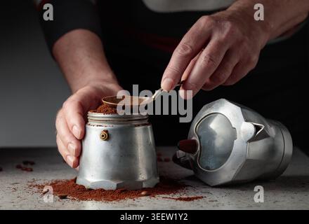 L'homme est versé du café moulu dans un pot de moka italien classique en aluminium. Une authentique cafetière italienne vintage, modèles des années 1950 à 1960 Banque D'Images