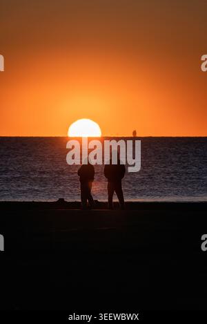 Homme et femme Silhouette regardant le soleil se lever au-dessus de l'océan Banque D'Images