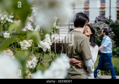 Gros plan de jeune couple multiculturel s'embrassant dans le parc de floraison printanière en Europe Banque D'Images