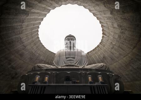 Statue de Bouddha assise sous le ciel rond dans le temple en béton Banque D'Images