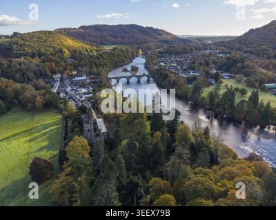 Vue aérienne de la cathédrale de Dunkeld et du pont de pierre enjambant la rivière Tay au milieu d'un feuillage d'automne dynamique et de collines ondulantes Dunkeld, Écosse, United Banque D'Images