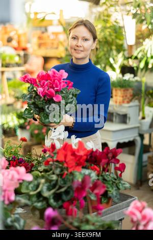 Client féminin choisissant cyclamen en pot dans le magasin de jardin de récipient Banque D'Images