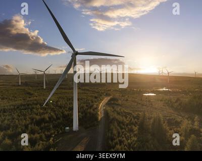 Vue aérienne des éoliennes à Eaglesham Moor entourées de denses forêts persistantes pendant un coucher de soleil doré Kilmarnock, Écosse, Royaume-Uni. Banque D'Images