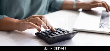 Gros plan des mains de femme travaillant avec la calculatrice et l'ordinateur portable Banque D'Images