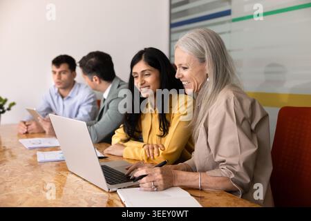Collègues féminines multiethniques travaillant ensemble sur ordinateur portable Banque D'Images